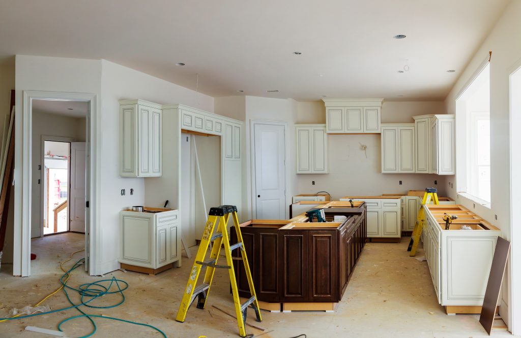 White kitchen in the middle of a renovation with ladders and tools throughout | smart time to start a remodel
